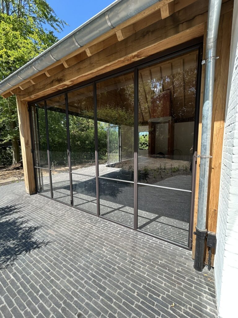 Stalen vouwramen in zwart gelakt staal onder een eiken overkapping