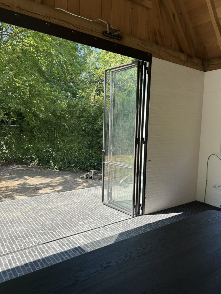 Opengevouwen stalen vouwraam met zicht op de tuin